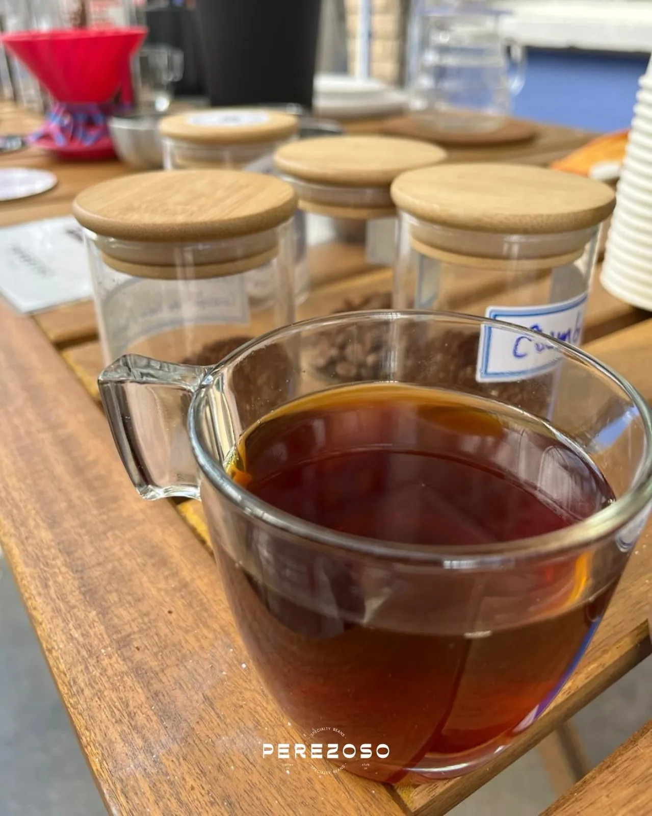 Tazas de cata y frascos con muestras de café sobre mesa de madera en el laboratorio